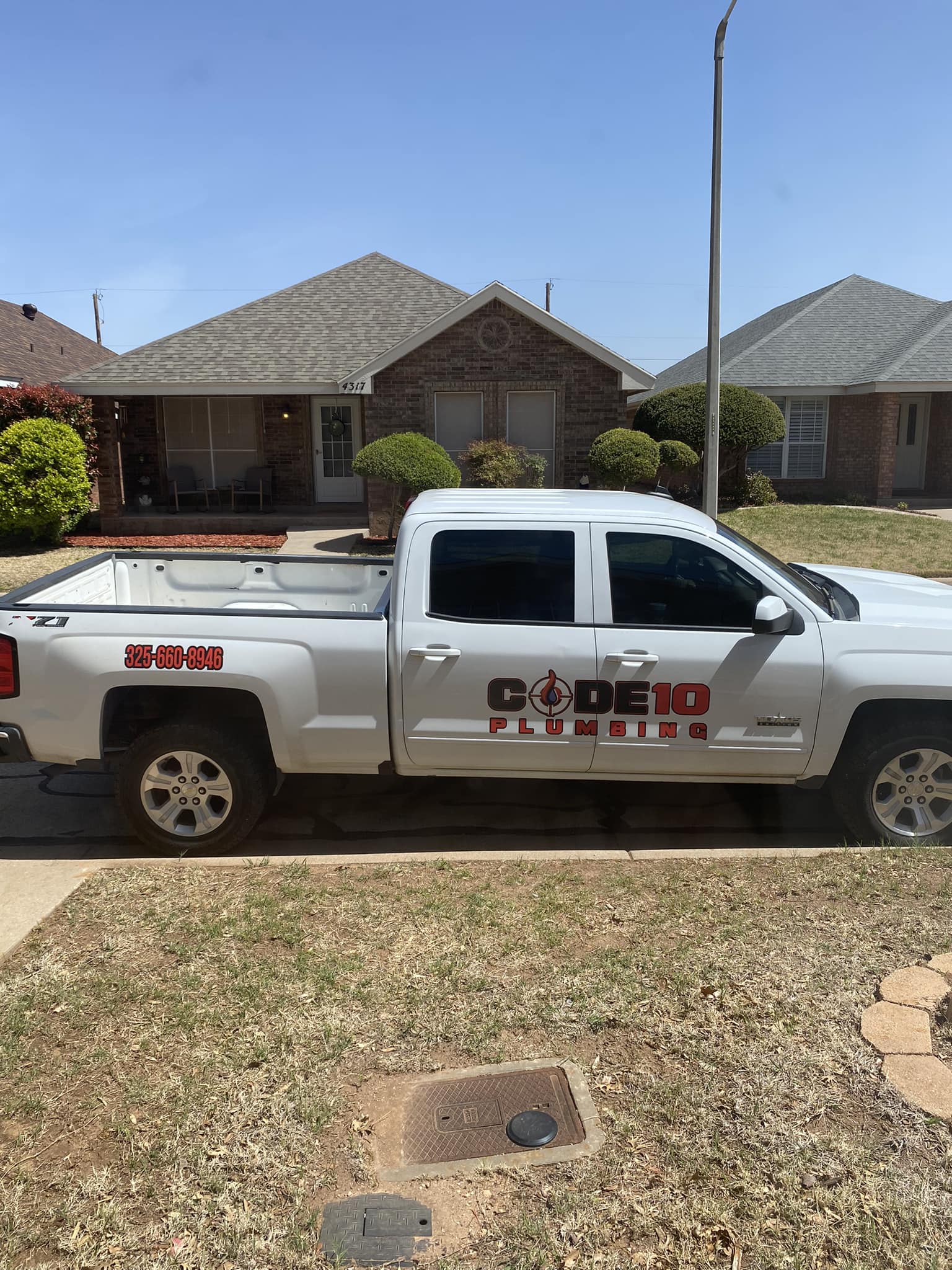 Code10 Plumbing work truck. White truck with Code10 Plumbing and the phone number 3256608946 written on the side.